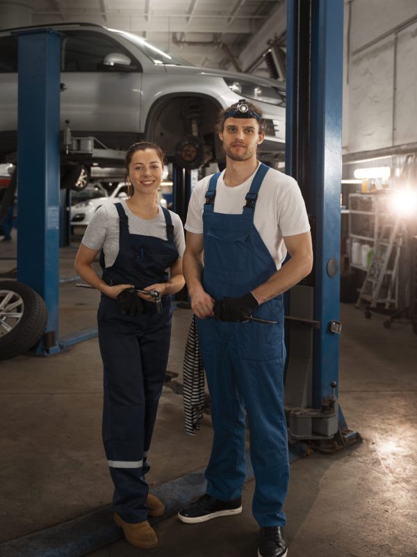male-female-mechanics-working-shop-car